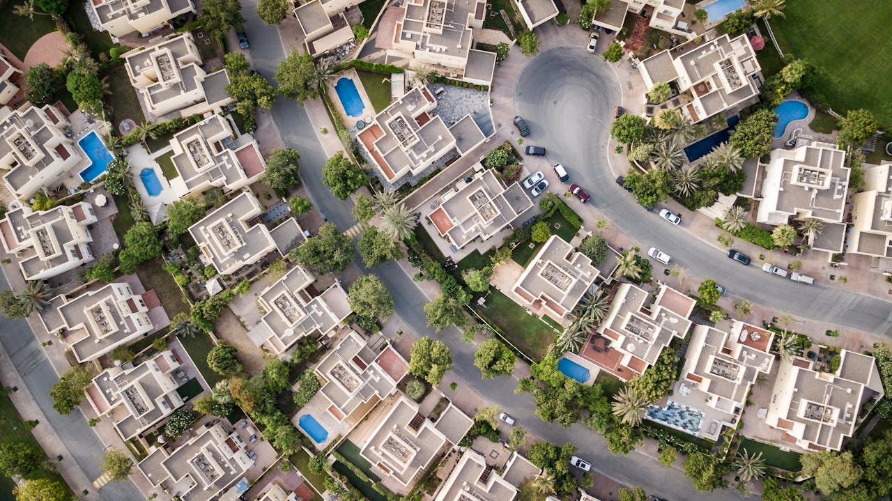 Services-01 Explore a stunning aerial view of a residential area in Dubai with lush greenery and swimming pools.