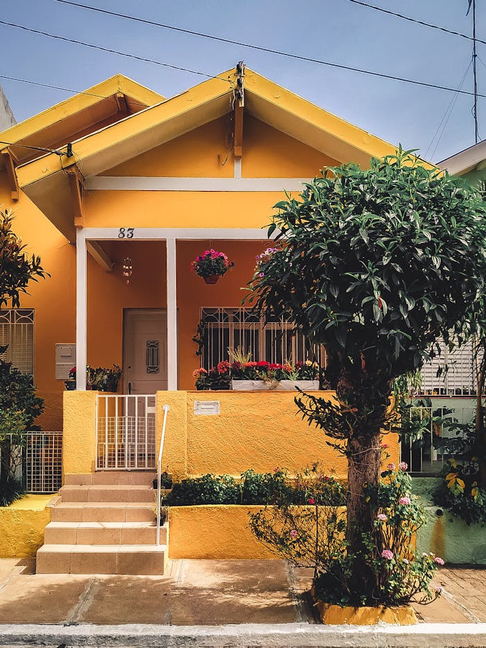 creative Bright yellow house with lush garden, vibrant flowers, and welcoming porch entrance.